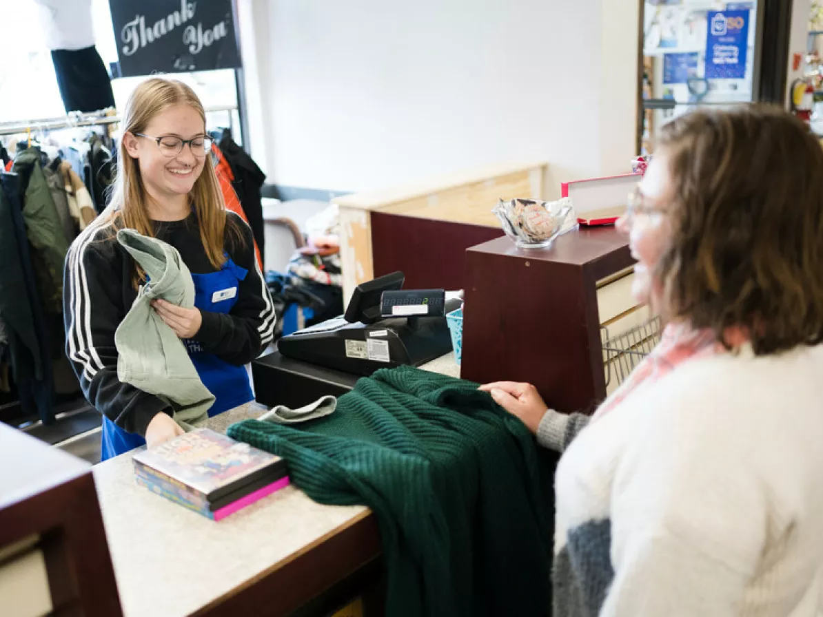 Amy Peters (cashier) processes Helena Neufeld's (customer) secondhand finds at the cash register of the Taber MCC Thrift Shop.