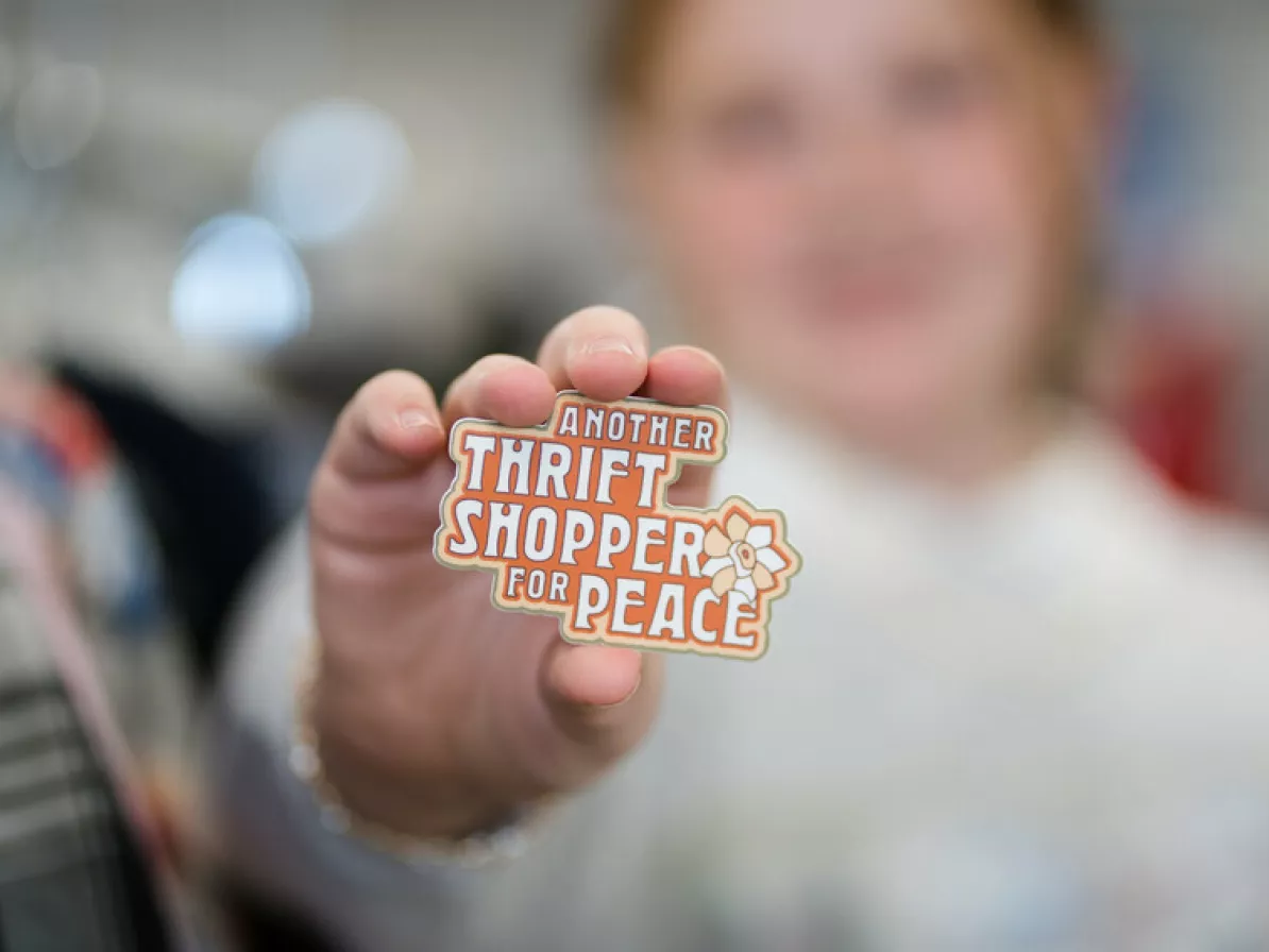 A customer holds up a patch that reads, "Another thrift shopper for peace" at the Taber MCC Thrift Shop.

These patches were created as part of a set to celebrate MCC Thrift's 50th anniversary. The