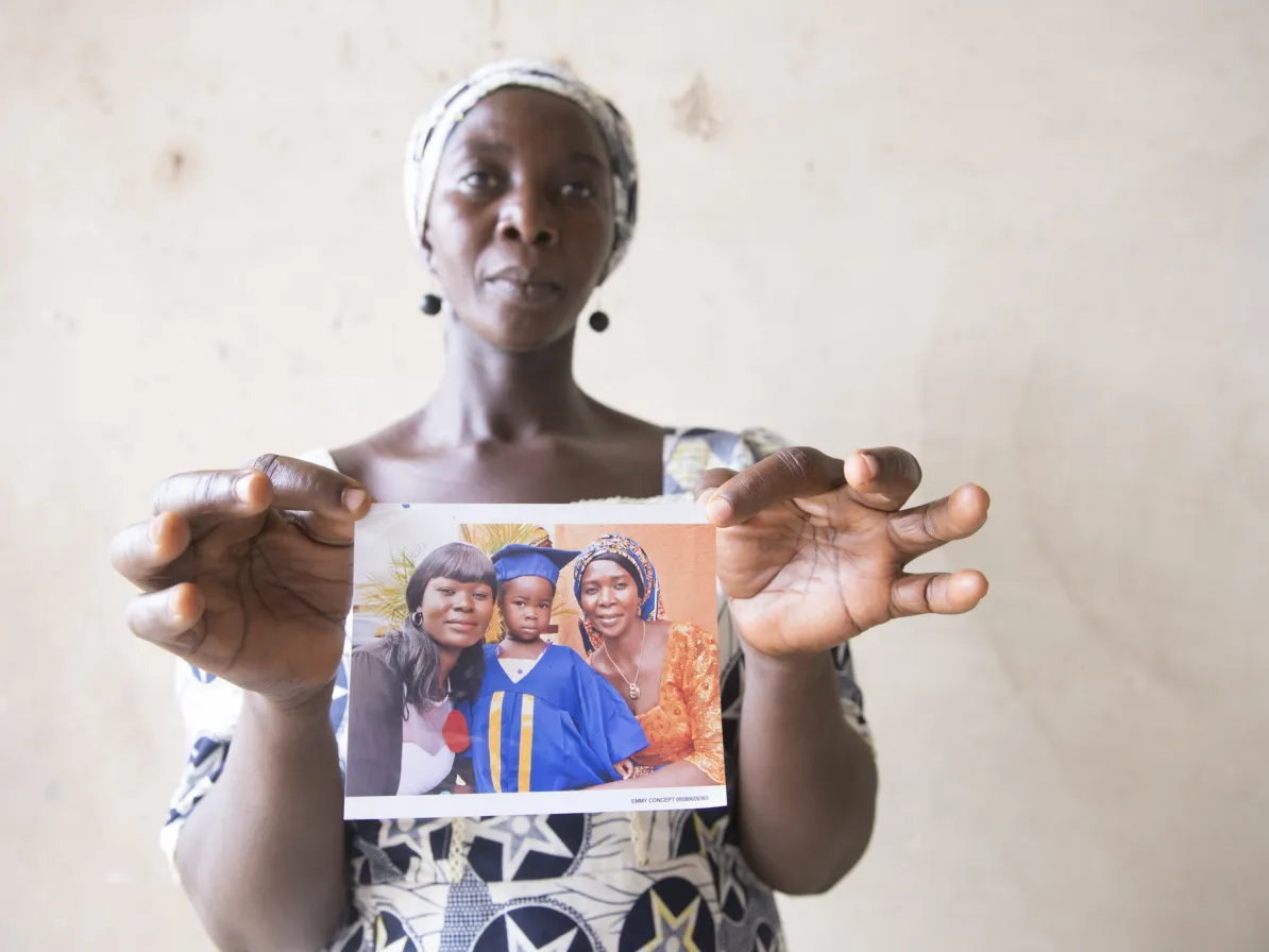 Workshop participant Naomi Philip holds a photo of her family before her husband Philip Mwada and three sons Moses, 14, Emmanuel, 12, and Haruna “Aaron”,10, who were all killed in 2014 while trying to
