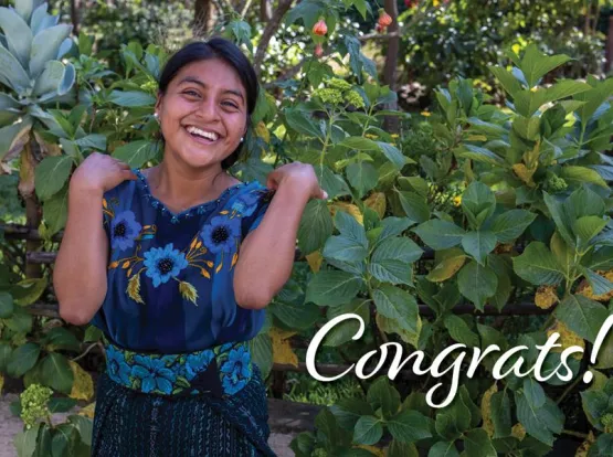 A smiling woman standing with the word "Congrats!"