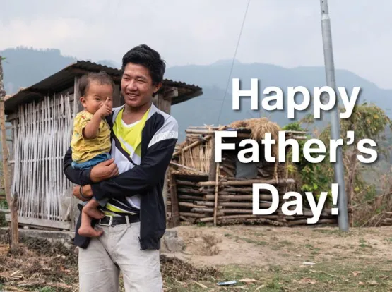 A smiling man holding a child with the words "Happy Father's Day!"