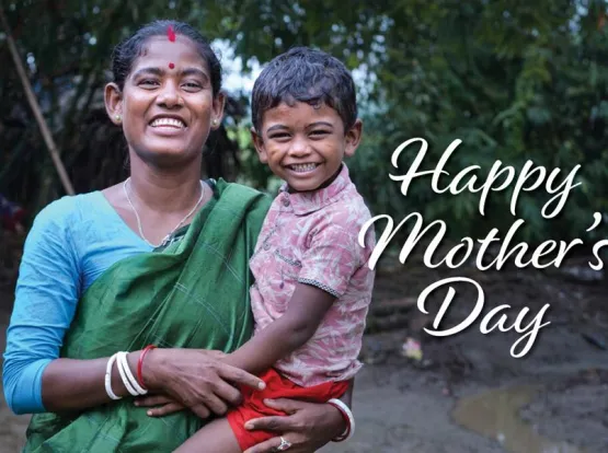 A smiling woman holding a child with the words "Happy Mother's Day"