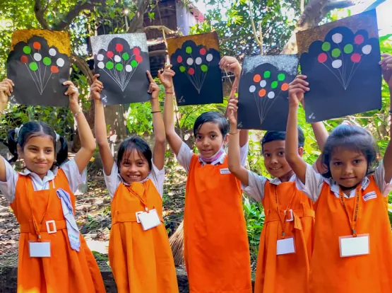 Five school girls hold up their art work.