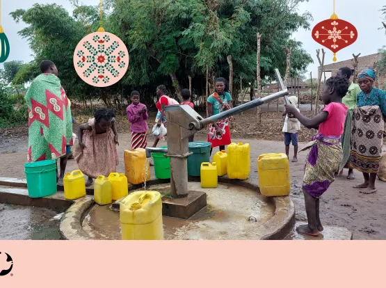 A group of children pumping water from a well. Christmas ornaments are imposed over the image with the MCC logo in the bottom left corner.