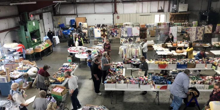 warehouse set up for fabric sale with several shoppers looking at fabric
