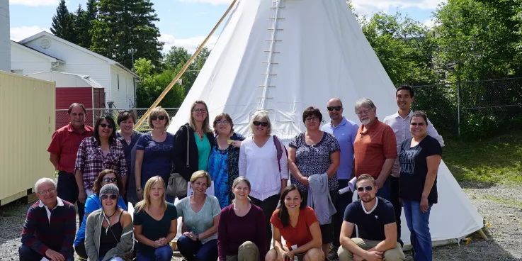 A group of people standing in front of a teepee