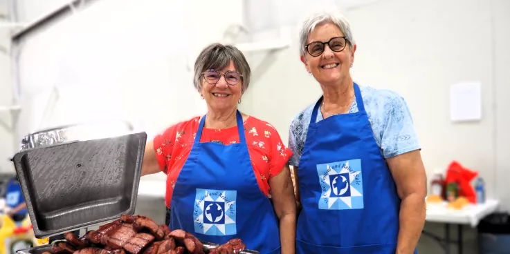 Two Festival volunteers at the MCC Festival for World Relief. With a chafing dish of Mennonite sausage