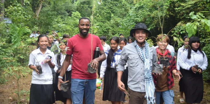 MCC Cambodia staff and students from a local school carry saplings to plant in a deforested area in the Monks Community Forest in northwest Cambodia.