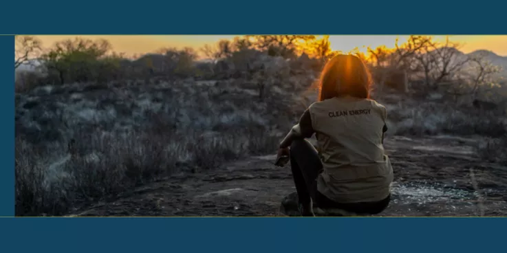 Woman sitting on a hill overlooking a dry field