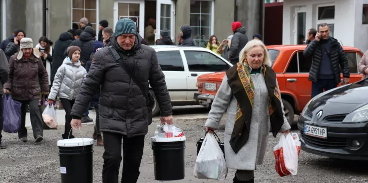 Man and woman holding relief kit buckets.