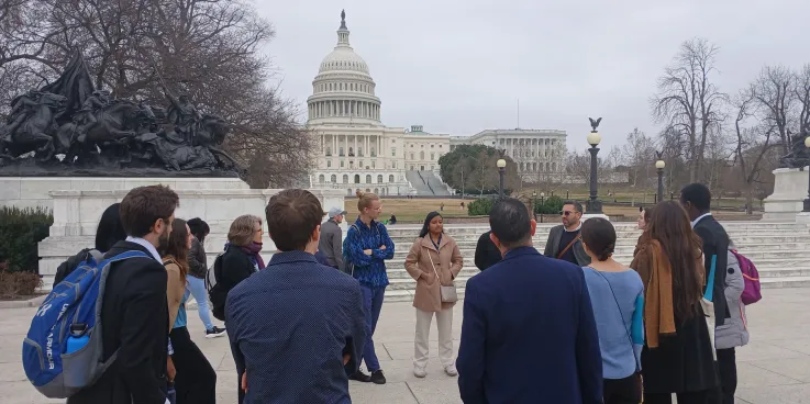 Group of young adults standing in a circle in front of the capital building