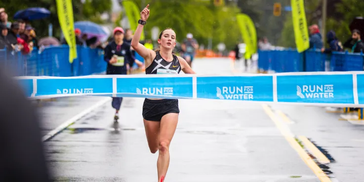 A female runner crossing the Run For Water finish line