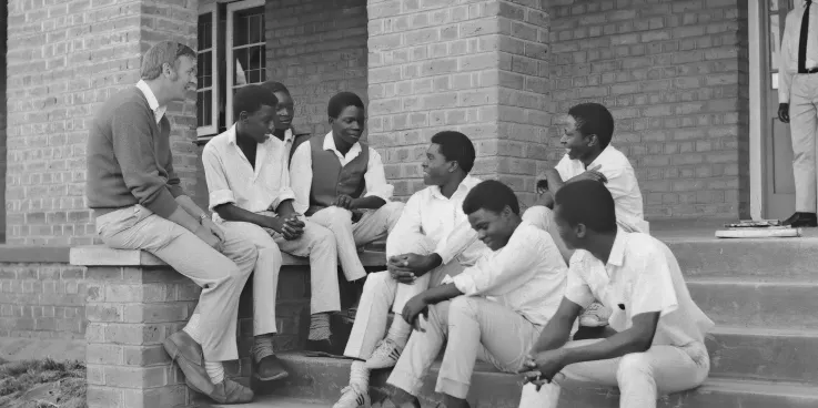 Group of young men sitting and chatting with an older man