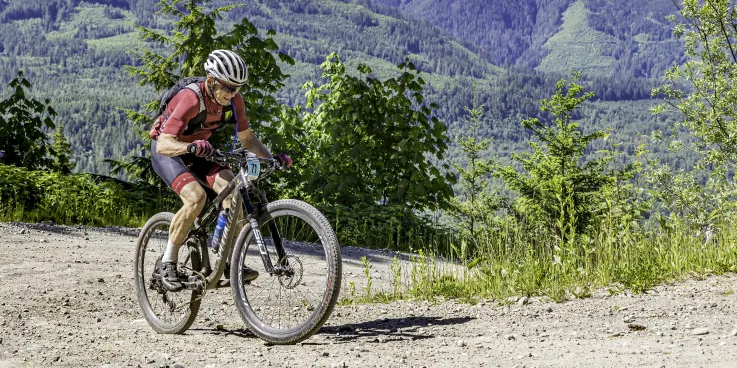 A man cycles uphill with mountains in the background