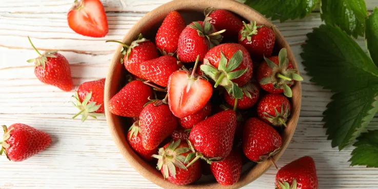 A bowl of strawberries from above with a bright background.