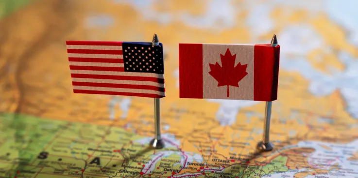A map of part of the US and with two small American and Canadian flags sitting on top of it.