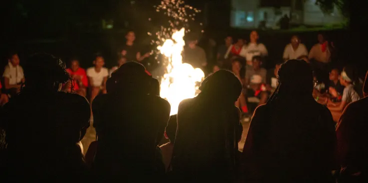 Four youth sit in front of campfire