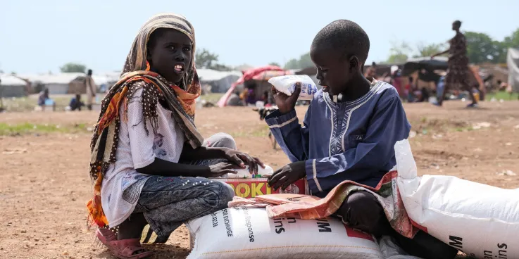 Zero Mawang Juch  (left) and Sudan Koang Ruei at the distribution site with a portion of food supplies. Each bag of sorghum is about 15kgs, so it is heavy for program participants to carry on their he