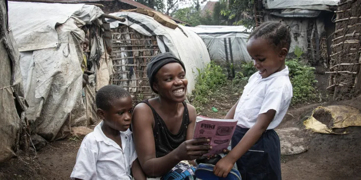 War-displaced Bahati Kamara Chance, center, checks her daughter Bulonza Amina’s notebook before Bulonza and Nelly Kabumba, left, go off to school. Chance continually checks her daughter's grades.