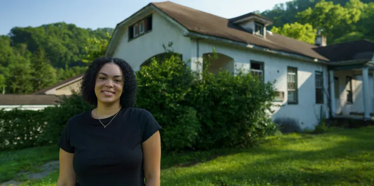 Tylah Cline, Dismukes Project Coordinator,  stands  in front of the Nurse‘s Home of the former Dismukes Hospital.