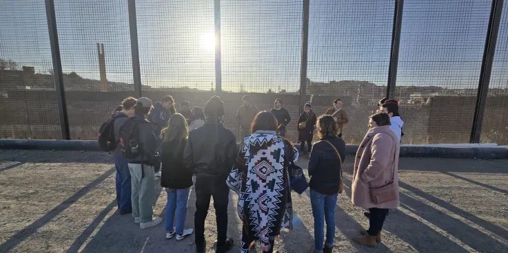 Saulo Padilla, MCC U.S. Migration Education Coordinator, speaks to MCC Borderlands Peace Camp participants in front of the U.S.-Mexico border wall in El Paso, Texas. The group lit a candle as a prayer