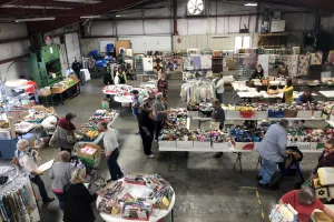warehouse set up for fabric sale with several shoppers looking at fabric