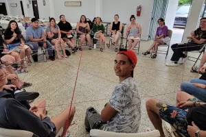Young people sitting in a circle connected by web of string.