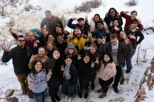 Young adults stand in a group pose in the snow.