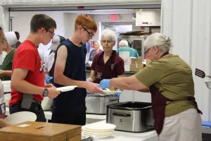 woman serving pancakes to two boys