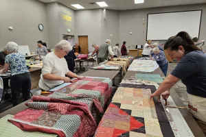 two women trim the edges of comforters 
