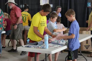 three boys stand around table packing hyiene kits