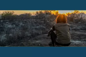 Woman sitting on a hill overlooking a dry field