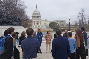 Group of young adults standing in a circle in front of the capital building