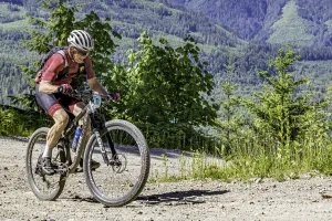 A man cycles uphill with mountains in the background