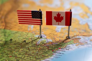 A map of part of the US and with two small American and Canadian flags sitting on top of it.