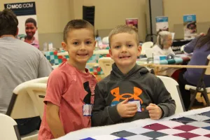 two boys stand by quilt