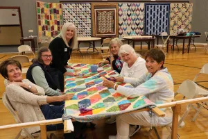 group of women sitting around a comforter