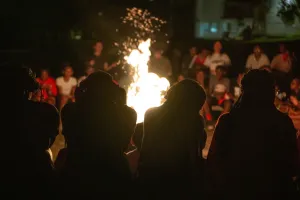 Four youth sit in front of campfire