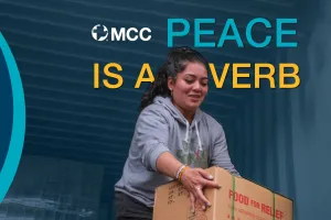 A woman unloading a truck, holding a box that says "Food for Relief." Text in the front reads, "MCC Peace is a Verb."