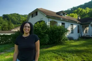 Tylah Cline, Dismukes Project Coordinator,  stands  in front of the Nurse‘s Home of the former Dismukes Hospital.