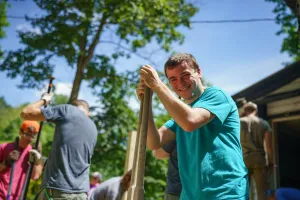 Micah Dodson, left, Appalachia Build staff, digs a hole for a post to support a wheelchair ramp in Kimball, West Virginia.