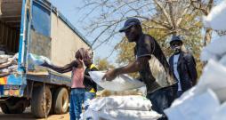 People in Africa unloading large white bags from a truck.