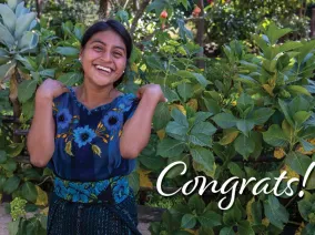 A smiling woman standing with the word "Congrats!"