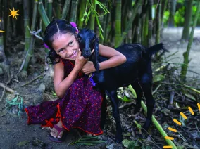 A girl embracing a goat.