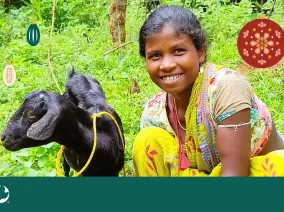A young girl smiling for a photo next to a goat. A Christmas ornament is overlayed in the top right corner with the MCC logo in the bottom left.
