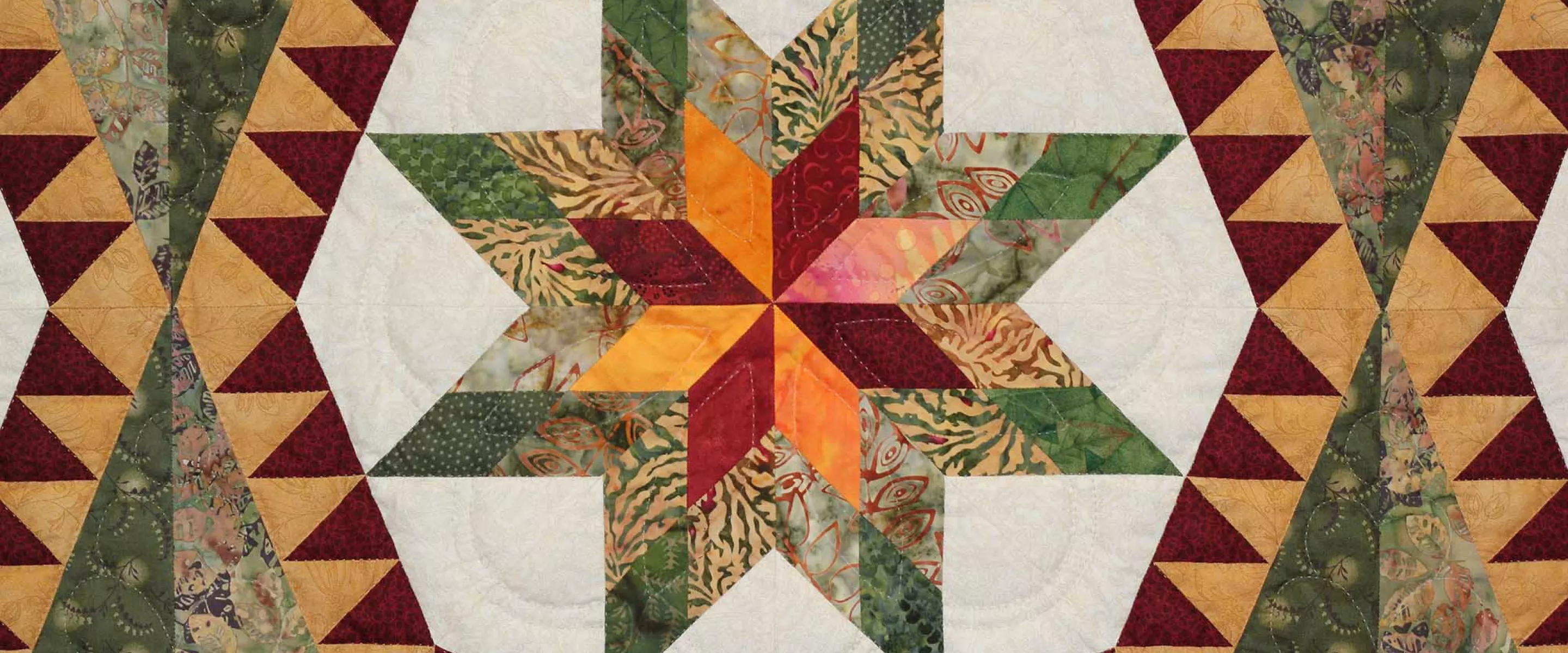 A close up of a quilt featuring a star shape made up of white, green, yellow and red fabric.