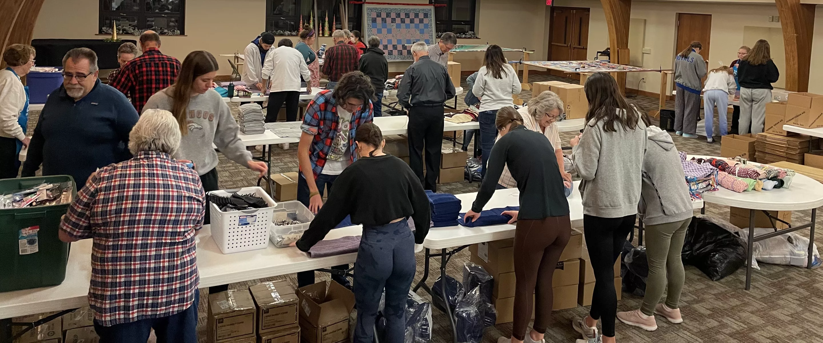  A group of volunteers assemble hygiene kits in large room.