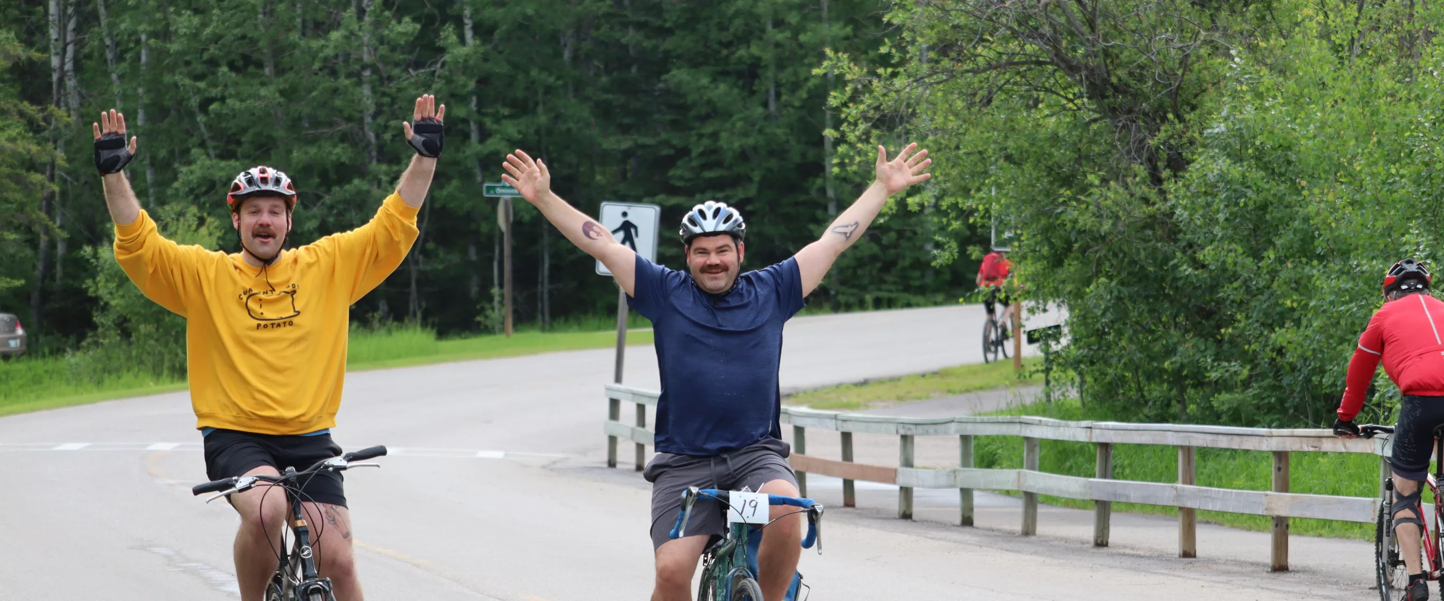 Two male cyclist in an open road with hands raised