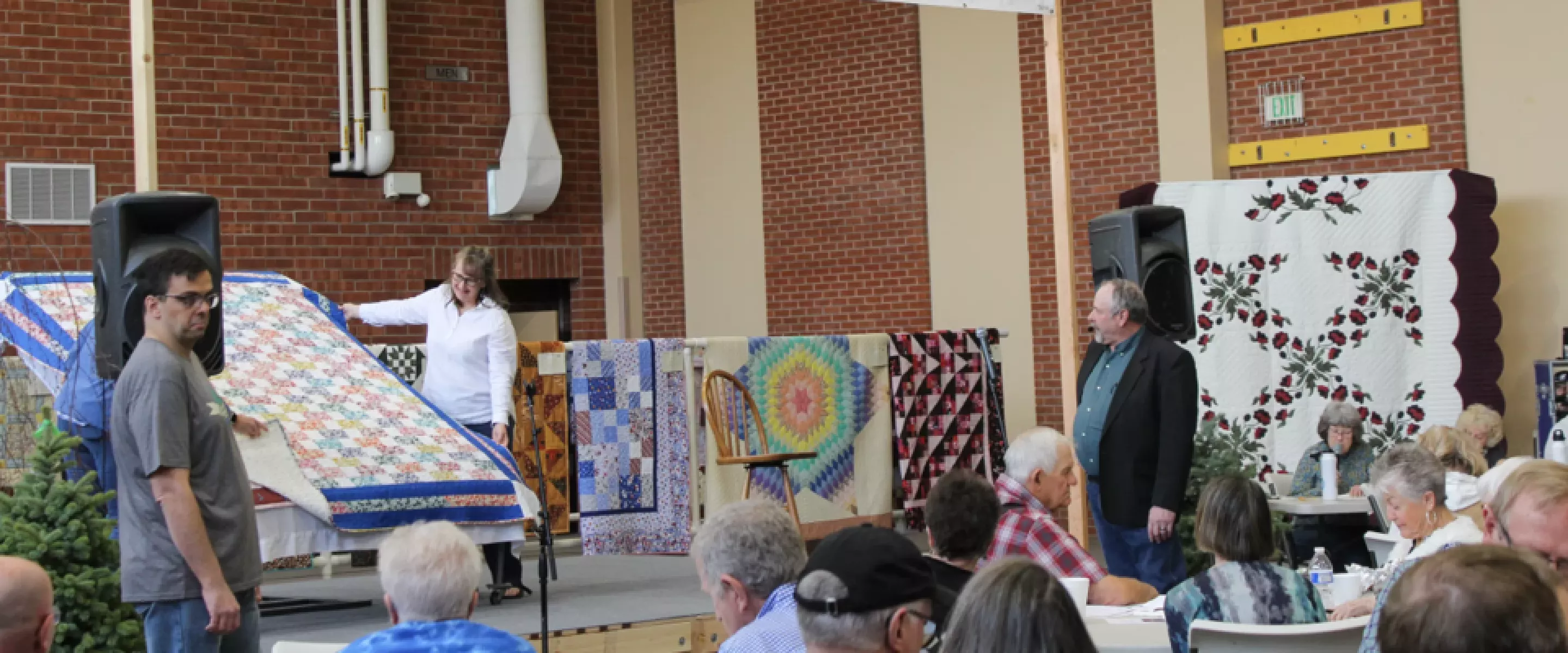  People sitting in audience for quilt auction.