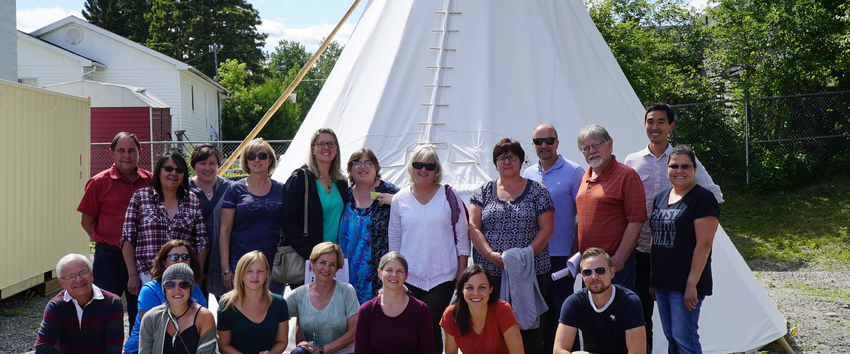 A group of people standing in front of a teepee